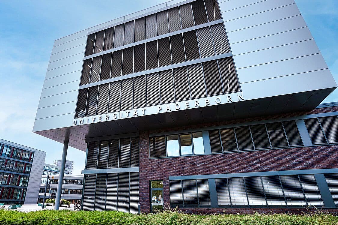 Main campus of University of Paderborn, featuring modern academic buildings, green spaces, and students walking on pathways.