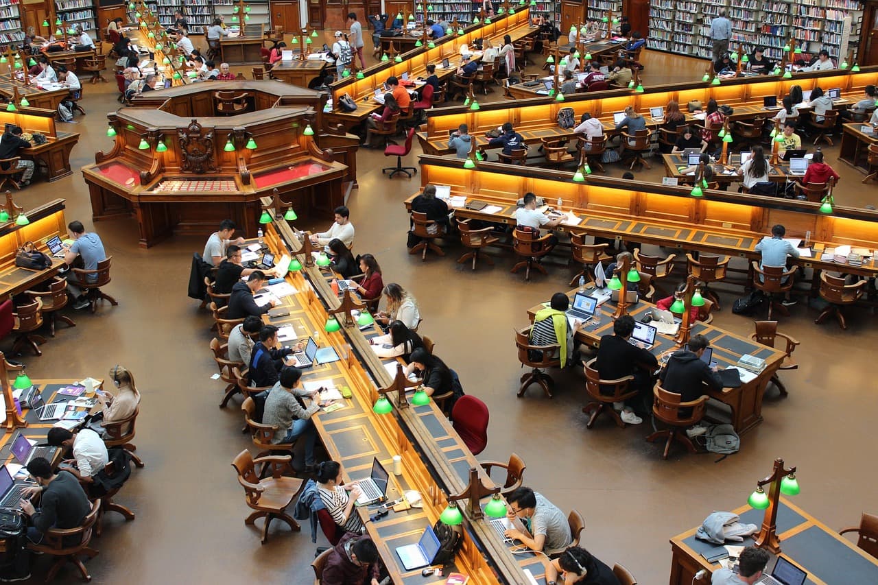 University students studying at long desks in a campus library