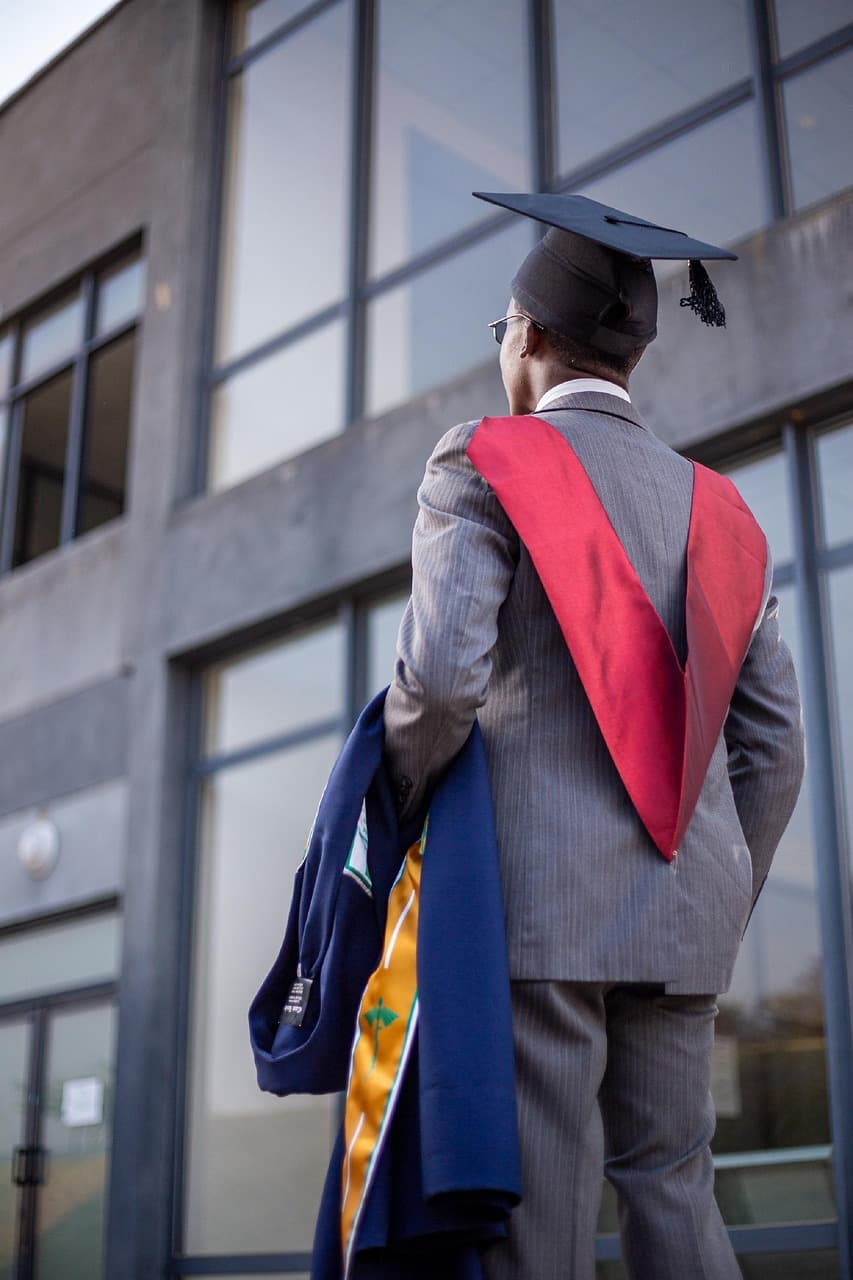Medical school graduate in a graduation gown and cap holding a diploma