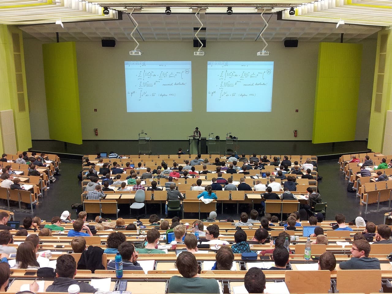 Students sitting in rows in a university lecture hall during a lecture